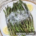 Grilled asparagus topped with Parmesan cheese on a plate.