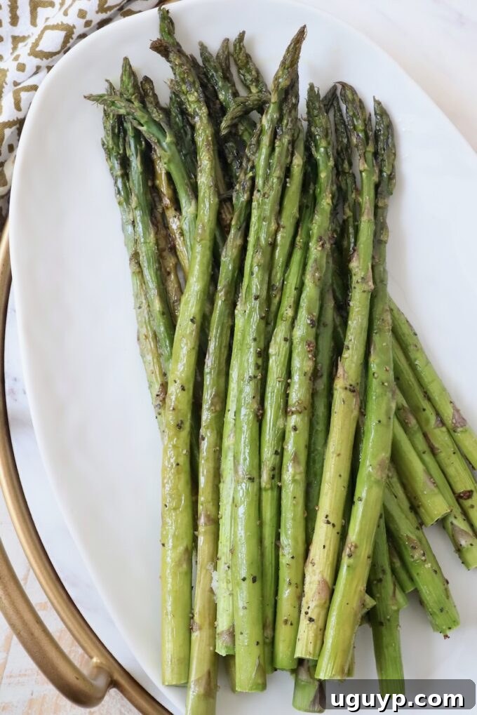 Perfectly roasted asparagus spears on a white plate, ready to be served.