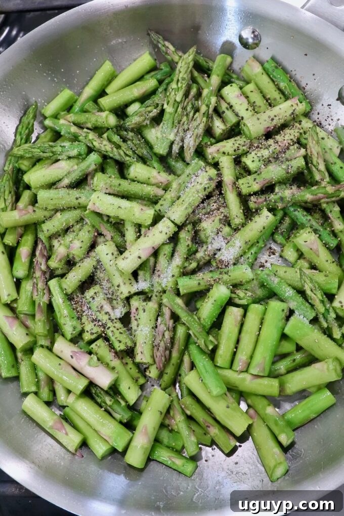 Diced and seasoned asparagus cooking in a hot skillet on the stovetop.