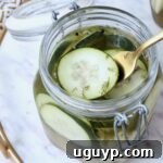Close-up of homemade pickle chips in a glass jar with a fork, highlighting their irresistible crunch.