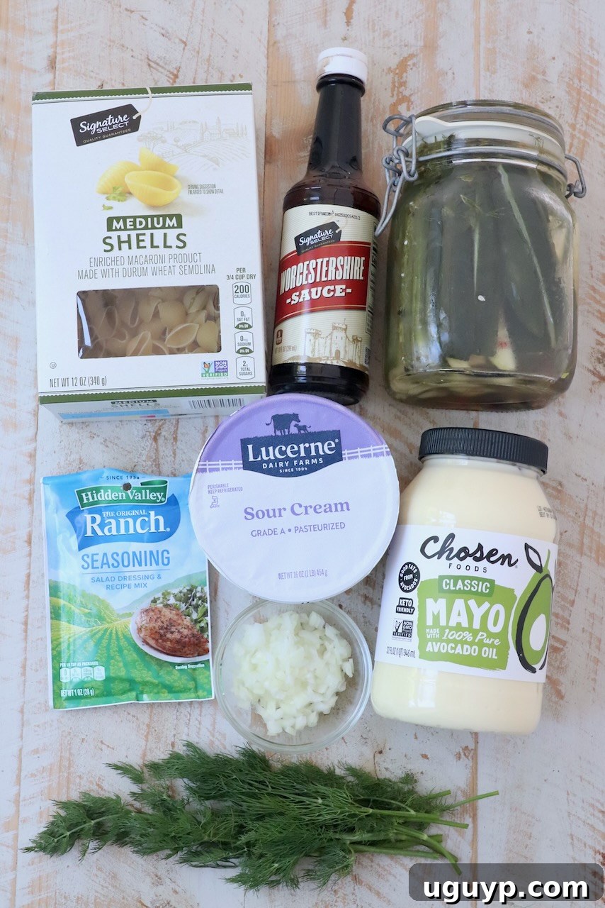 ingredients for dill pickle pasta salad on white wood board
