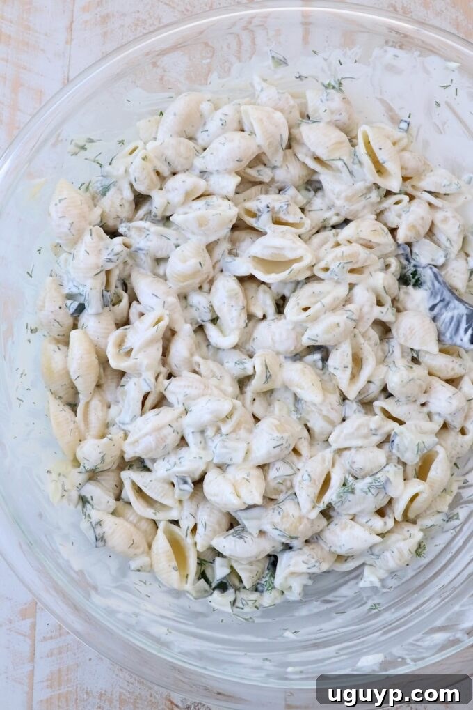 pickle pasta salad ingredients mixed together in large glass bowl