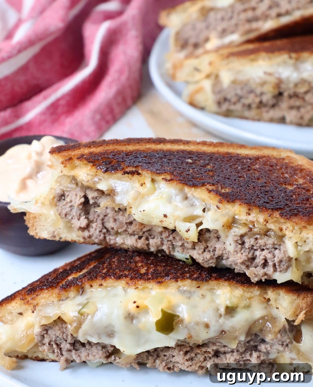A fully assembled patty melt, sliced in half and arranged on a plate, ready to be enjoyed.