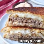 Cooked patty melt sandwich cut in half on a plate, ready to eat.