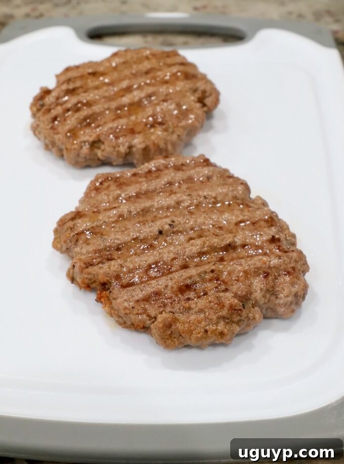 Perfectly cooked and browned burger patties resting on a cutting board.