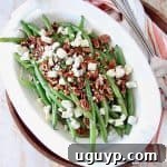 Overhead image of fresh green beans in serving bowl with pecans and blue cheese