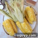 Cooked corn on the cob on a marble serving tray, golden and ready to enjoy.