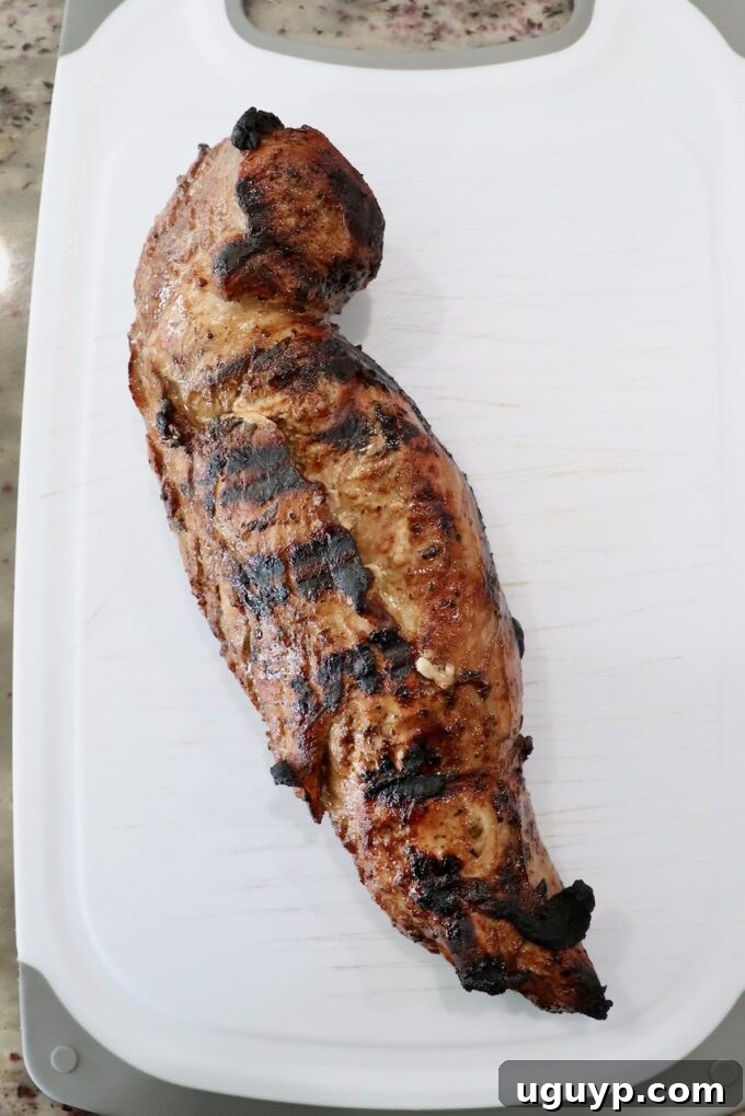 Cooked grilled pork tenderloin resting on a cutting board