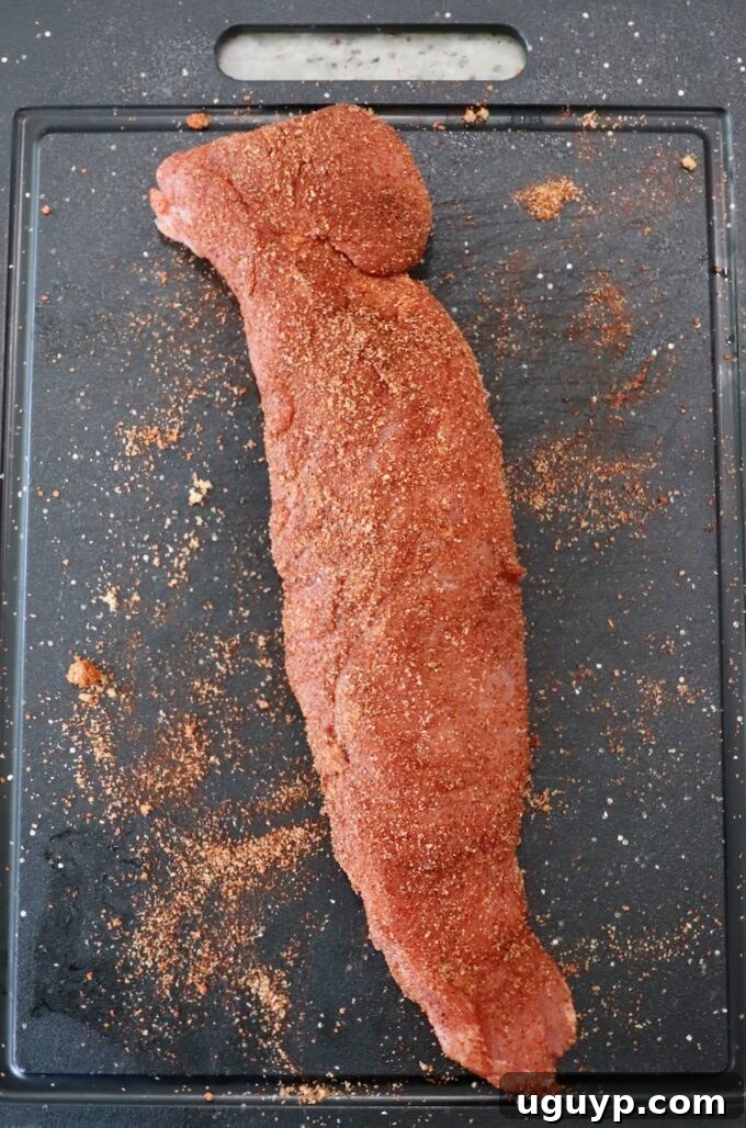 Seasoned pork tenderloin on cutting board.