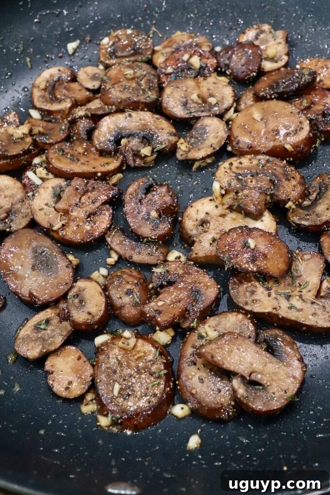 Perfectly sautéed mushrooms glistening in a large skillet, having absorbed rich flavors.
