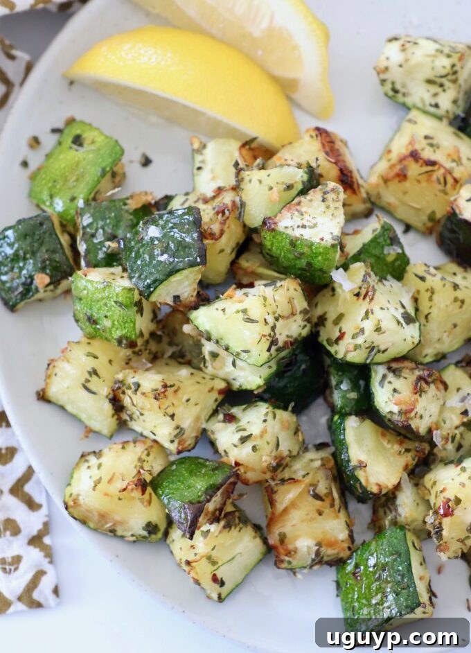 Cooked diced zucchini on a plate, garnished with fresh herbs
