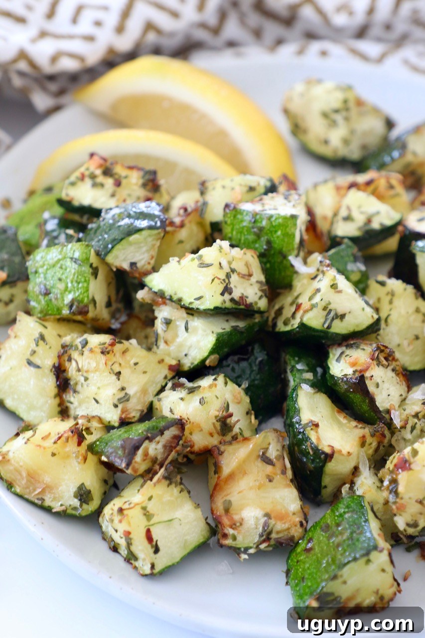Diced cooked zucchini on a plate with fresh lemon wedges, ready for plating