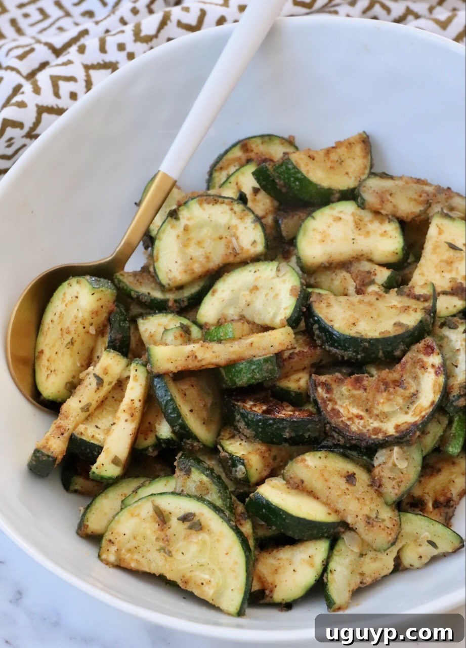Sautéed zucchini in a bowl with a serving spoon, garnished with fresh herbs