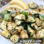 Cooked cubed zucchini on a plate, garnished with fresh herbs