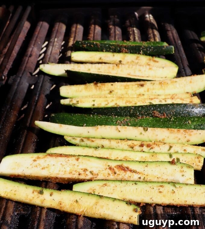 Zucchini spears cooking on a hot grill with visible grill marks