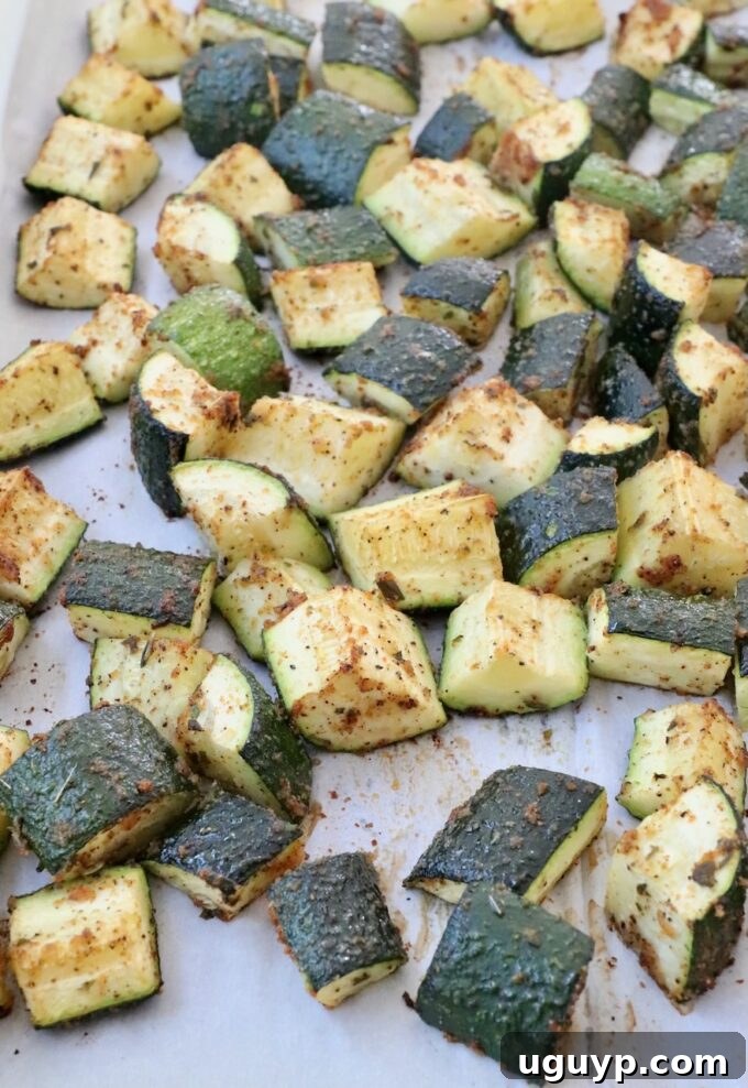 Cooked diced zucchini on a parchment-lined baking sheet after roasting