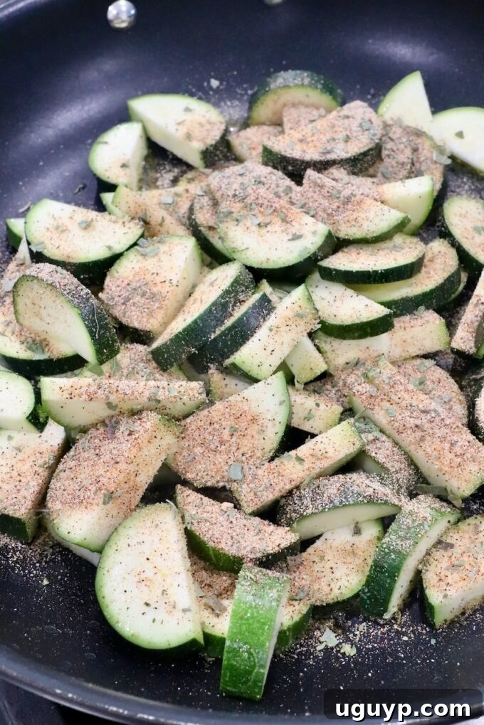 Seasoned zucchini slices in a large skillet on the stovetop