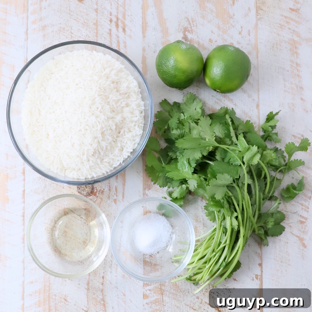 A flat lay photograph showcasing all the fresh ingredients required for cilantro lime rice, neatly arranged on a white wooden board.