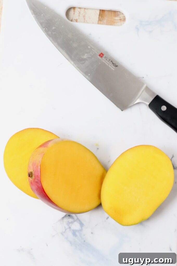 Perfectly sliced mango cheeks resting on a cutting board, ready for dicing or scooping.