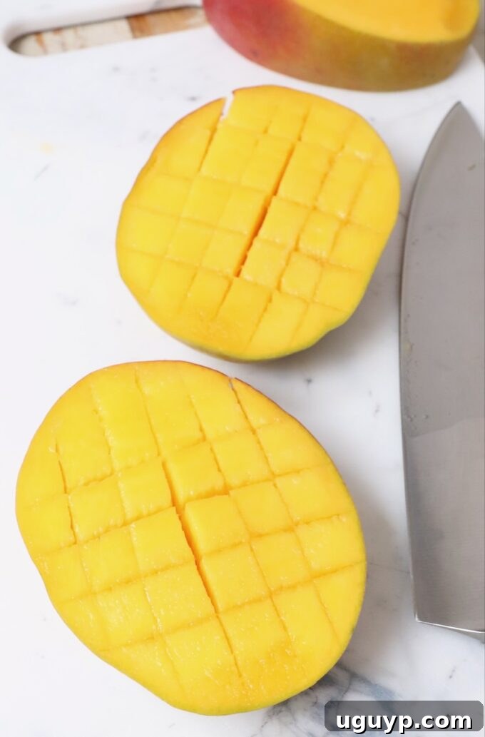 Mango flesh scored into precise cubes while still in its skin, demonstrating the cross-hatch cutting technique.