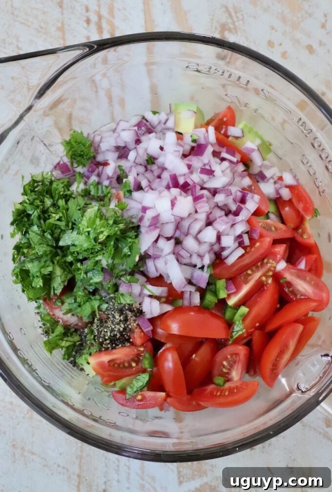 diced veggies in glass bowl with cilantro, salt and pepper