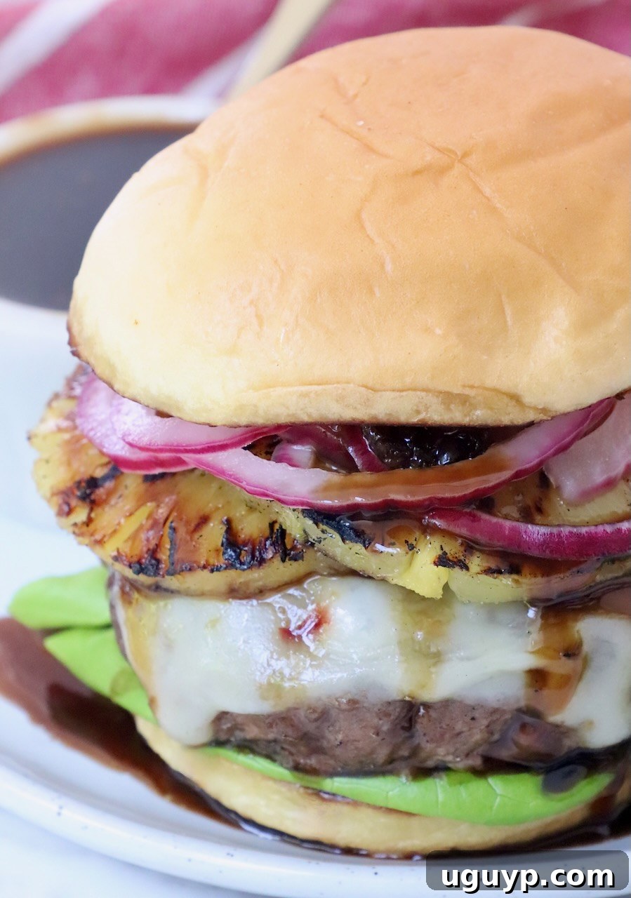 cheeseburger on plate topped with grilled pineapple and pickled onions