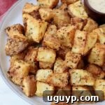 Crispy, seasoned roasted cubed potatoes ready to be served on a plate.