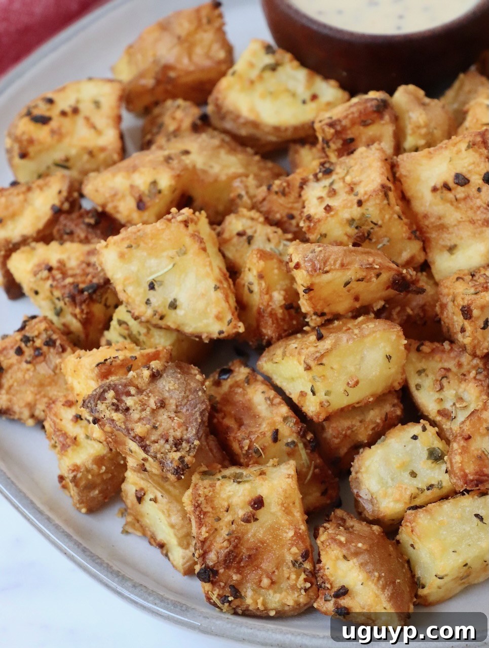 A serving of golden brown, crispy air fryer roasted potatoes on a plate, lightly garnished with fresh herbs.