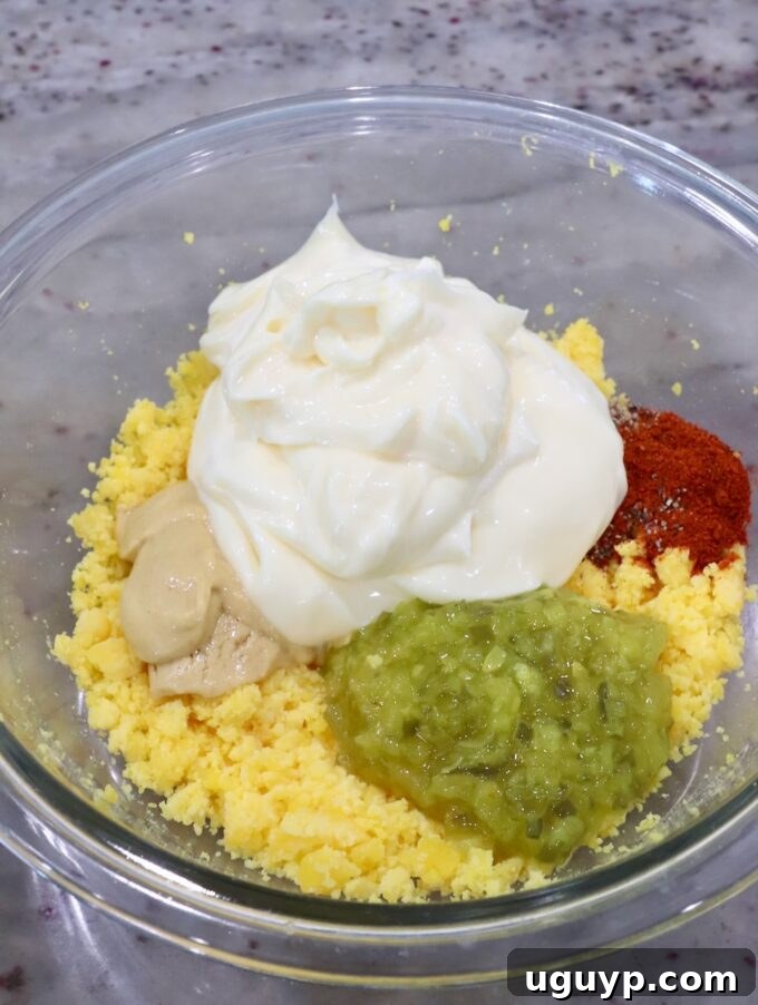 mashed egg yolks in a glass bowl with mayonnaise, relish, dijon mustard and spices