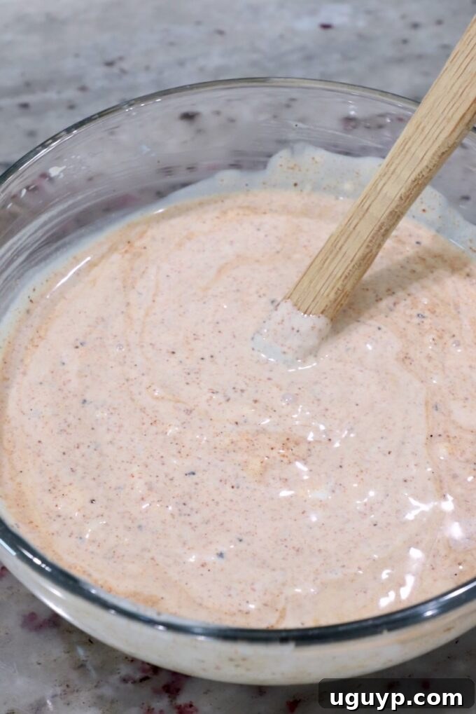 Creamy chili lime dressing prepared in a glass bowl with a spatula.