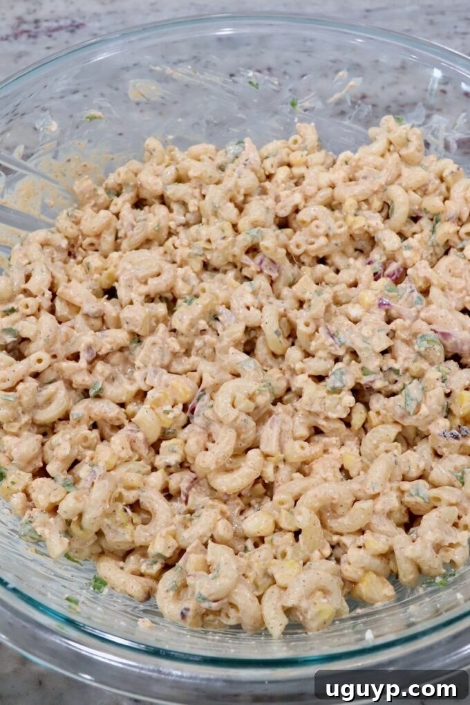 Fully assembled Mexican street corn pasta salad, ready for chilling, in a large glass bowl.