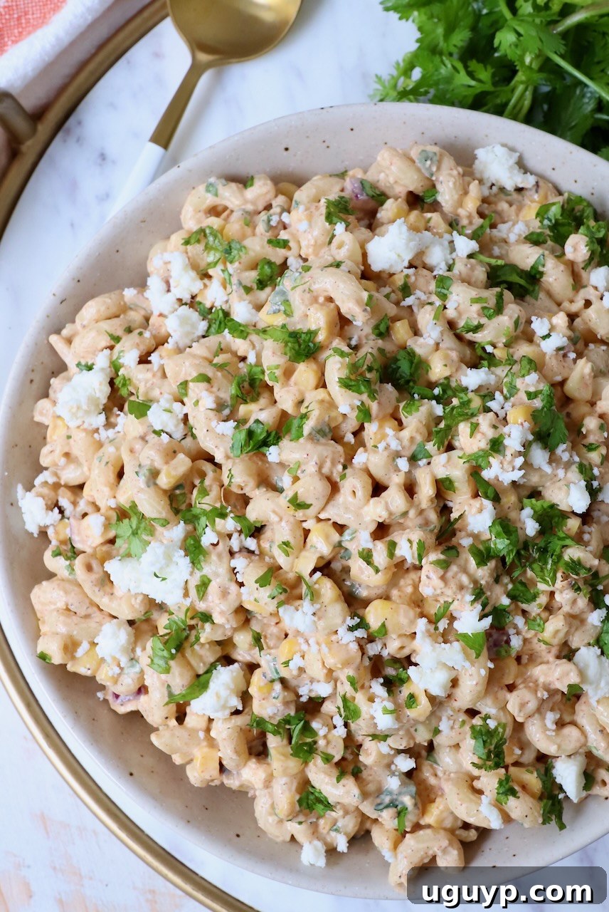 Prepared Mexican street corn pasta salad in a decorative bowl, garnished with fresh herbs.