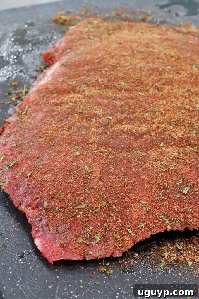 flank steak covered in seasoning on cutting board