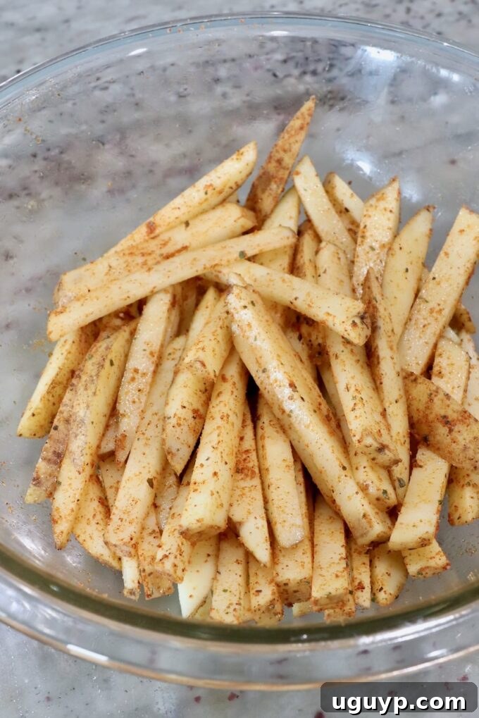 seasoned potatoes sliced into fries in glass bowl