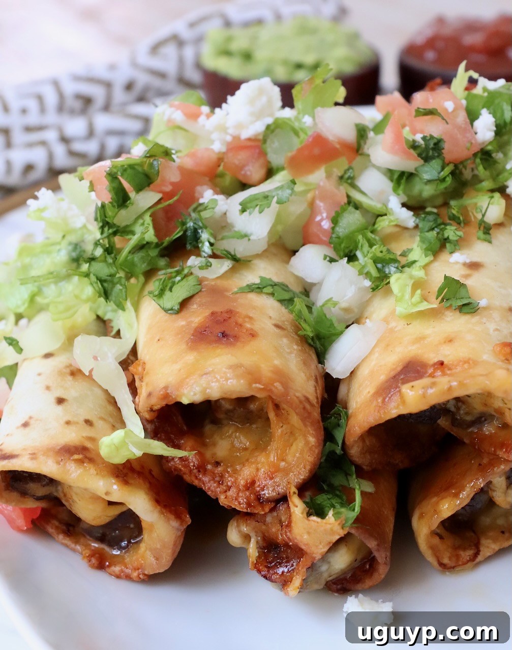 Crispy homemade beef taquitos stacked on a plate with fresh pico de gallo, ready to serve.