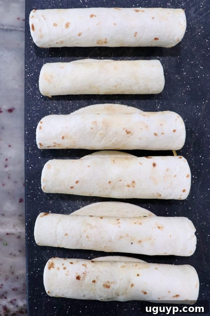 Several uncooked taquitos, tightly rolled with their delicious filling, arranged neatly on a cutting board, ready for the air fryer or oven.