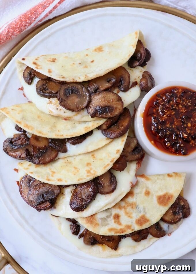 A beautifully assembled mushroom and cheese taco on a plate, paired with a small bowl of spicy salsa macha.
