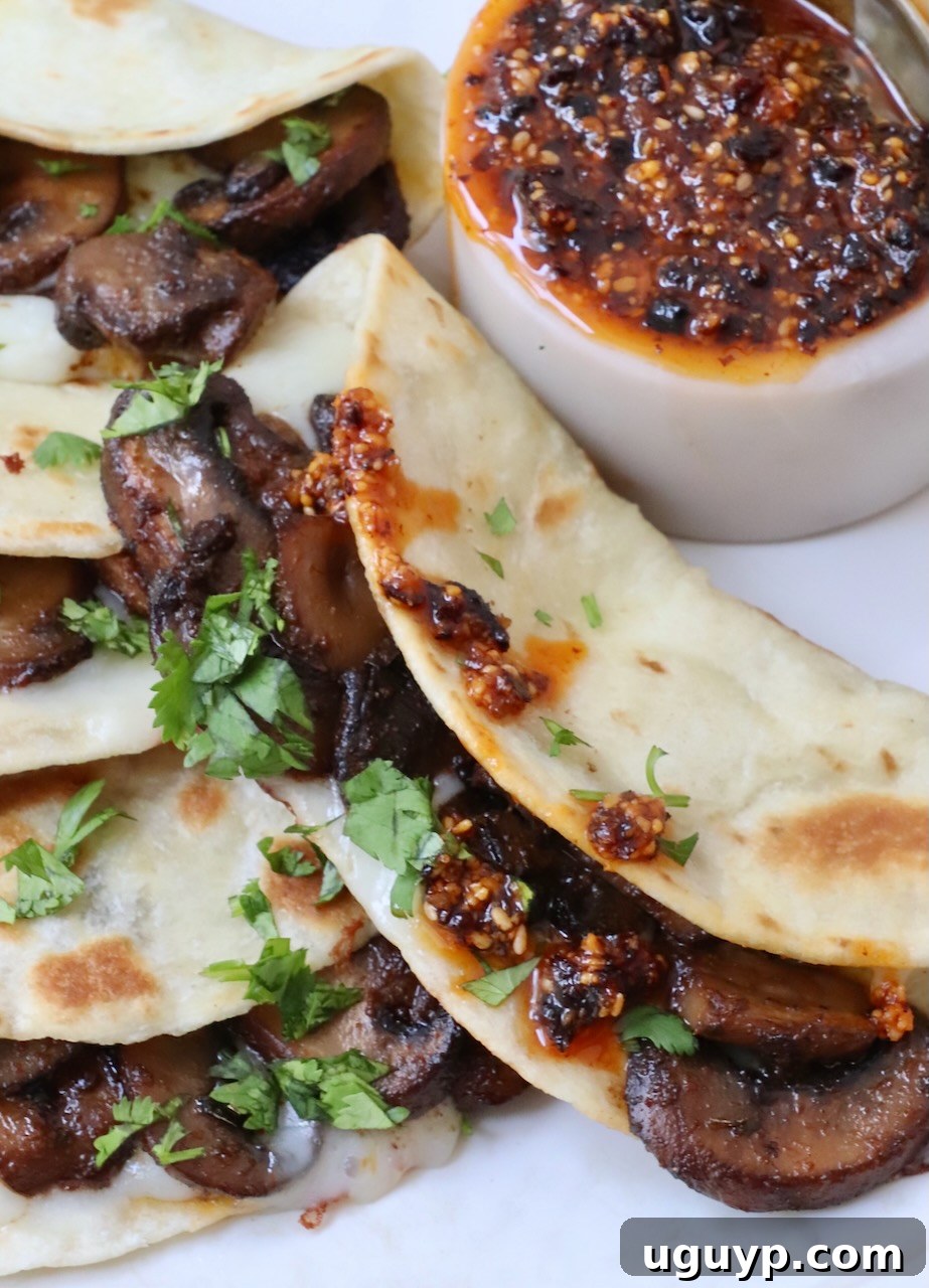 A close-up of mushroom tacos beautifully arranged on a plate, with a side of vivid salsa macha, inviting you to indulge.