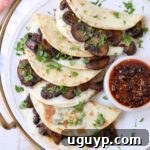 mushroom tacos stacked up on plate with a small bowl of salsa macha on the side
