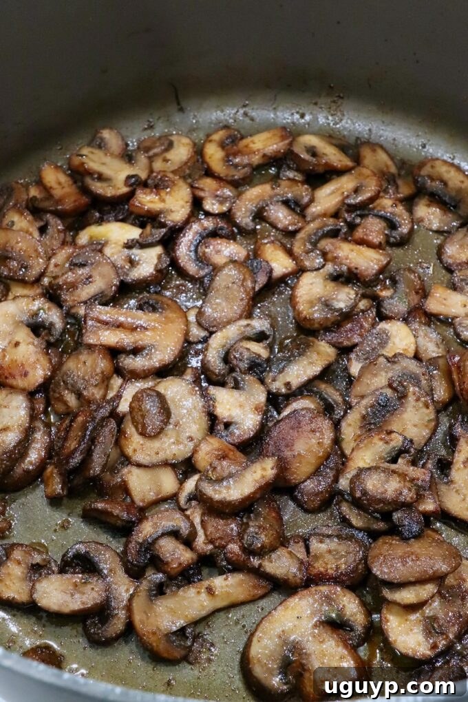 Fully cooked and seasoned sliced mushrooms in a large pot, ready to be added to tacos.