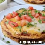 Mexican pizza on plate topped with diced tomatoes and fresh cilantro