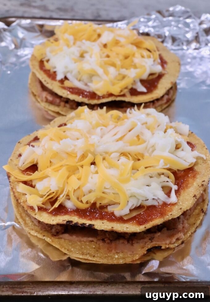 uncooked Mexican pizzas on a foil-lined baking sheet