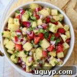 pineapple salsa in bowl surrounded by tortilla chips on a plate