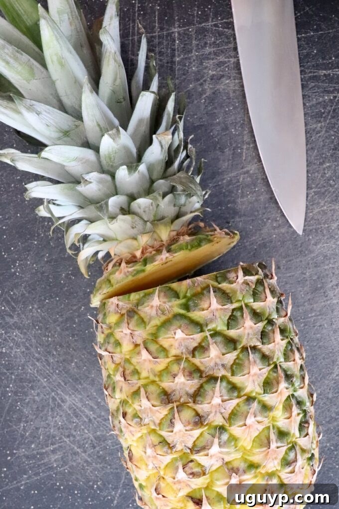 fresh pineapple with its leafy crown removed on a cutting board, ready for the next step