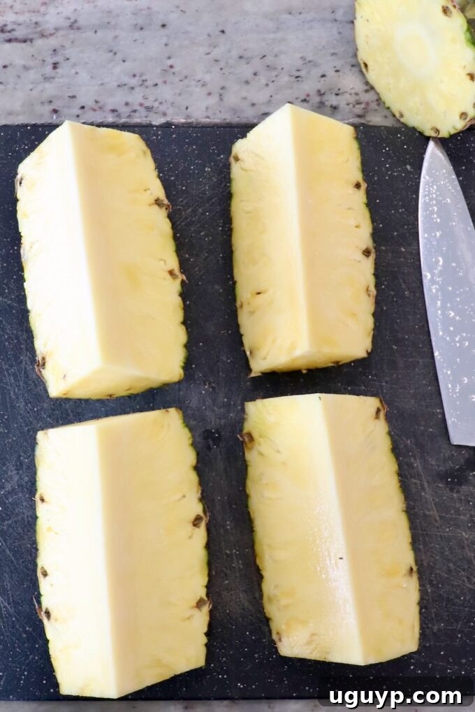 fresh pineapple sliced into four equal pieces on a cutting board, revealing the inner fruit