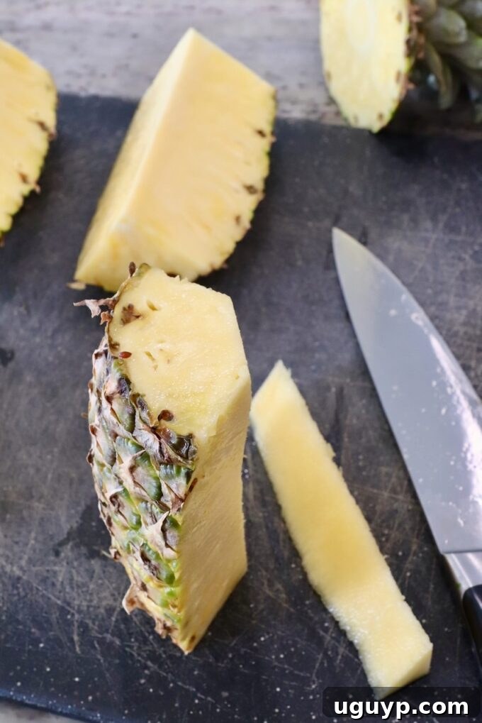 sliced pineapple on a cutting board with the tough central core carefully removed