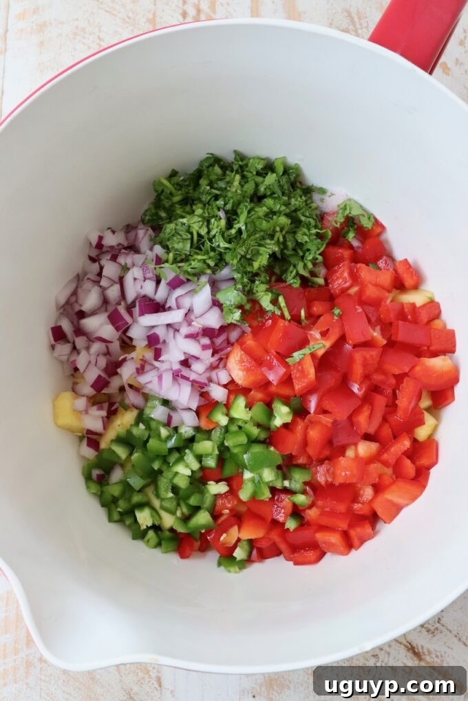diced vegetables and pineapple in a large mixing bowl, ready to be combined into salsa