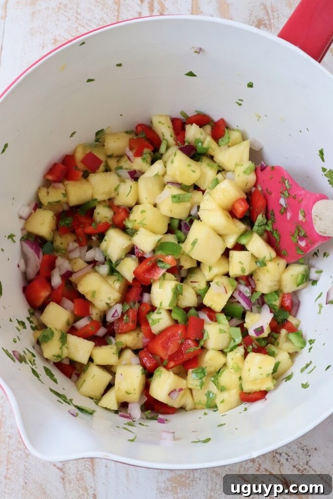 pineapple salsa mixed in a large bowl with a spatula, showing its vibrant, fresh texture