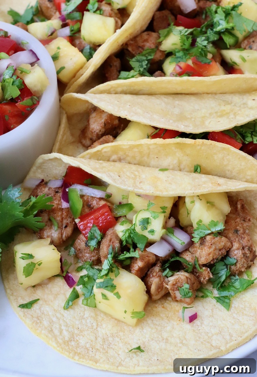 A vibrant plate of pork tacos topped with pineapple salsa, showcasing a colorful and delicious meal.