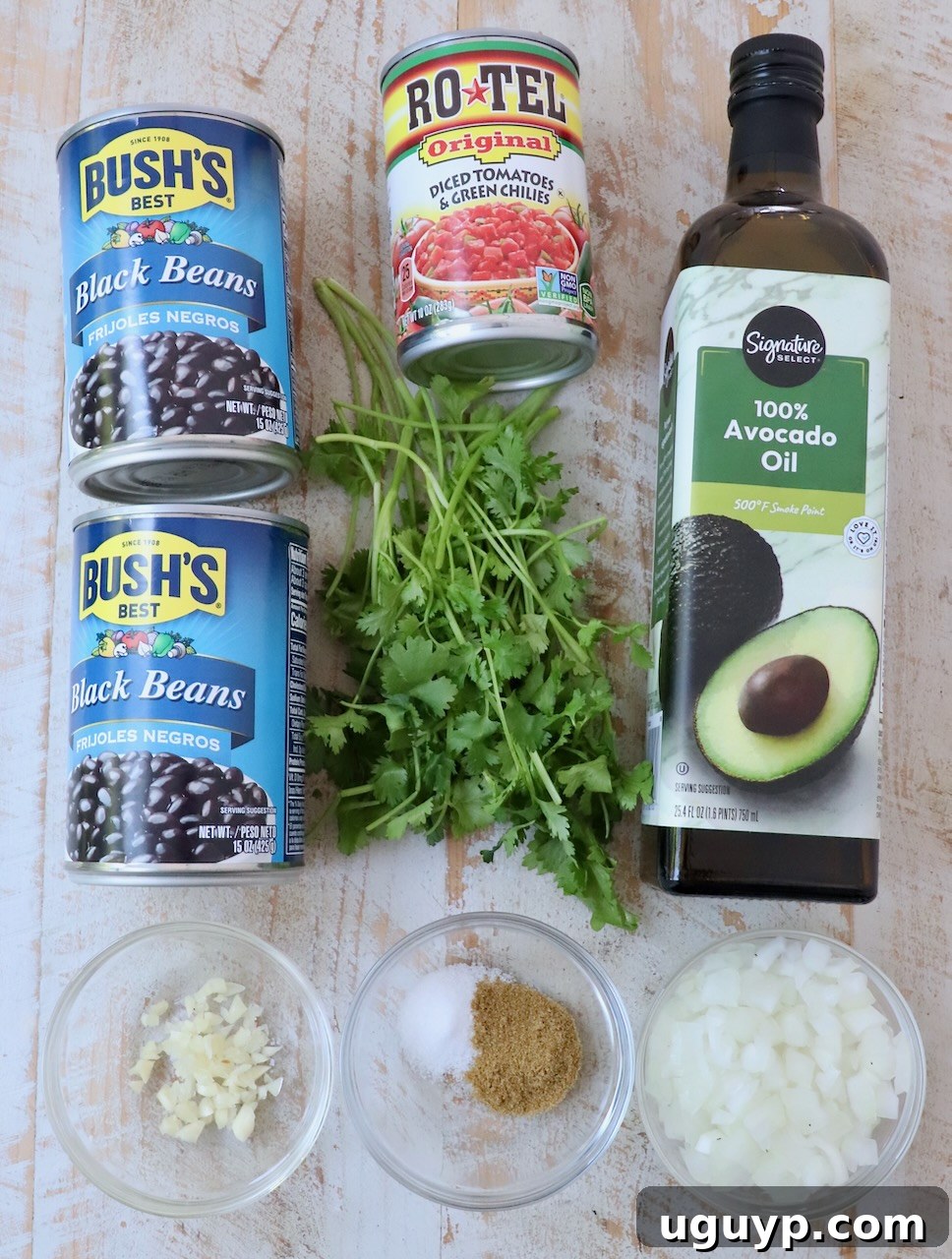 An overhead shot showcasing all the fresh and canned ingredients meticulously arranged on a rustic white wooden board, ready for making Mexican black beans.
